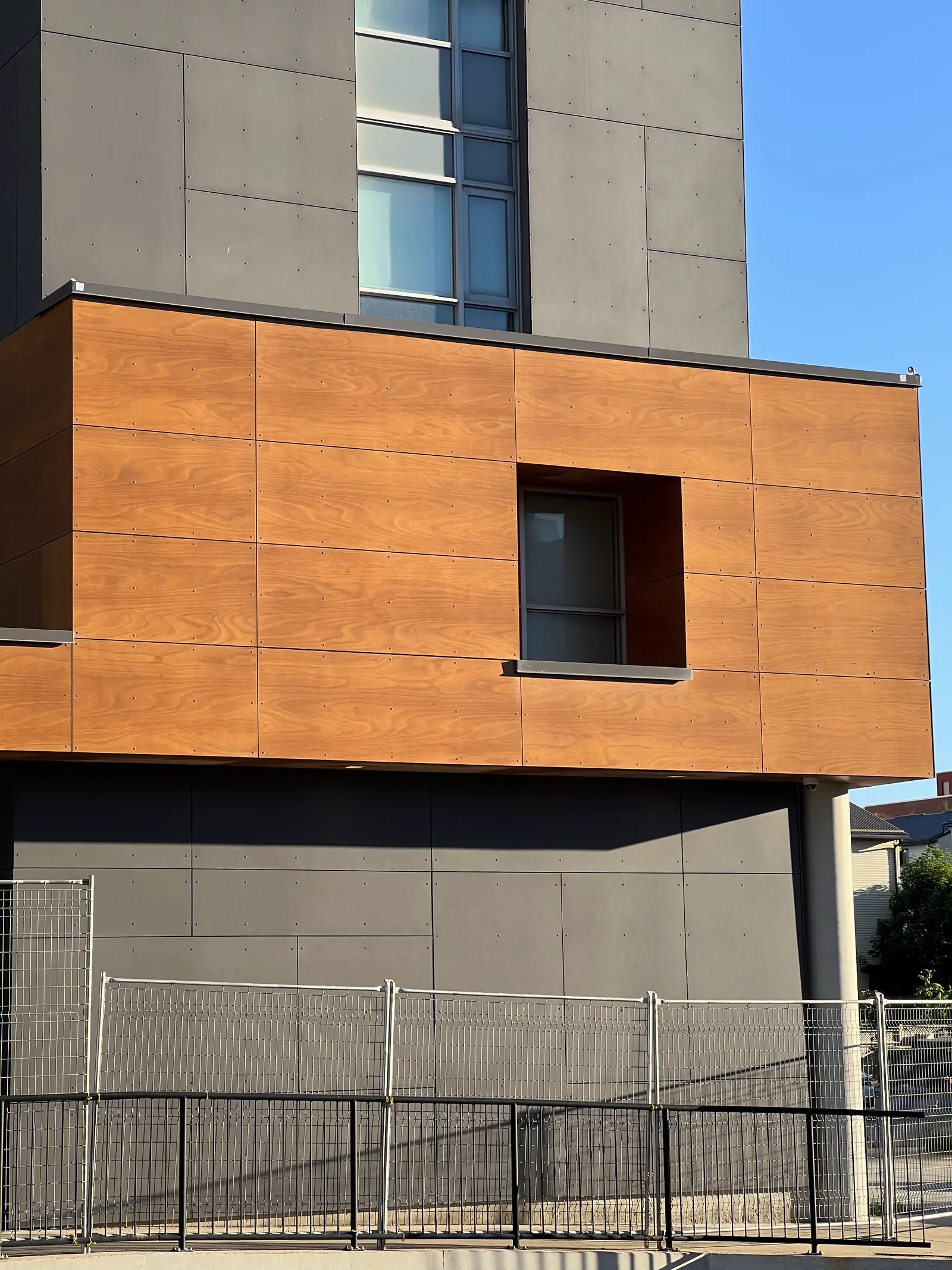 Wood-finish panel volume on a multi-residential tower podium